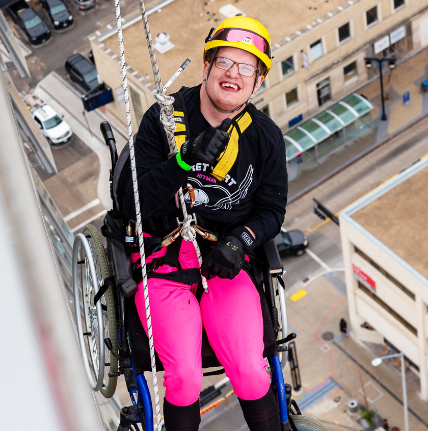A woman in a wheelchair scaling the side of a building.